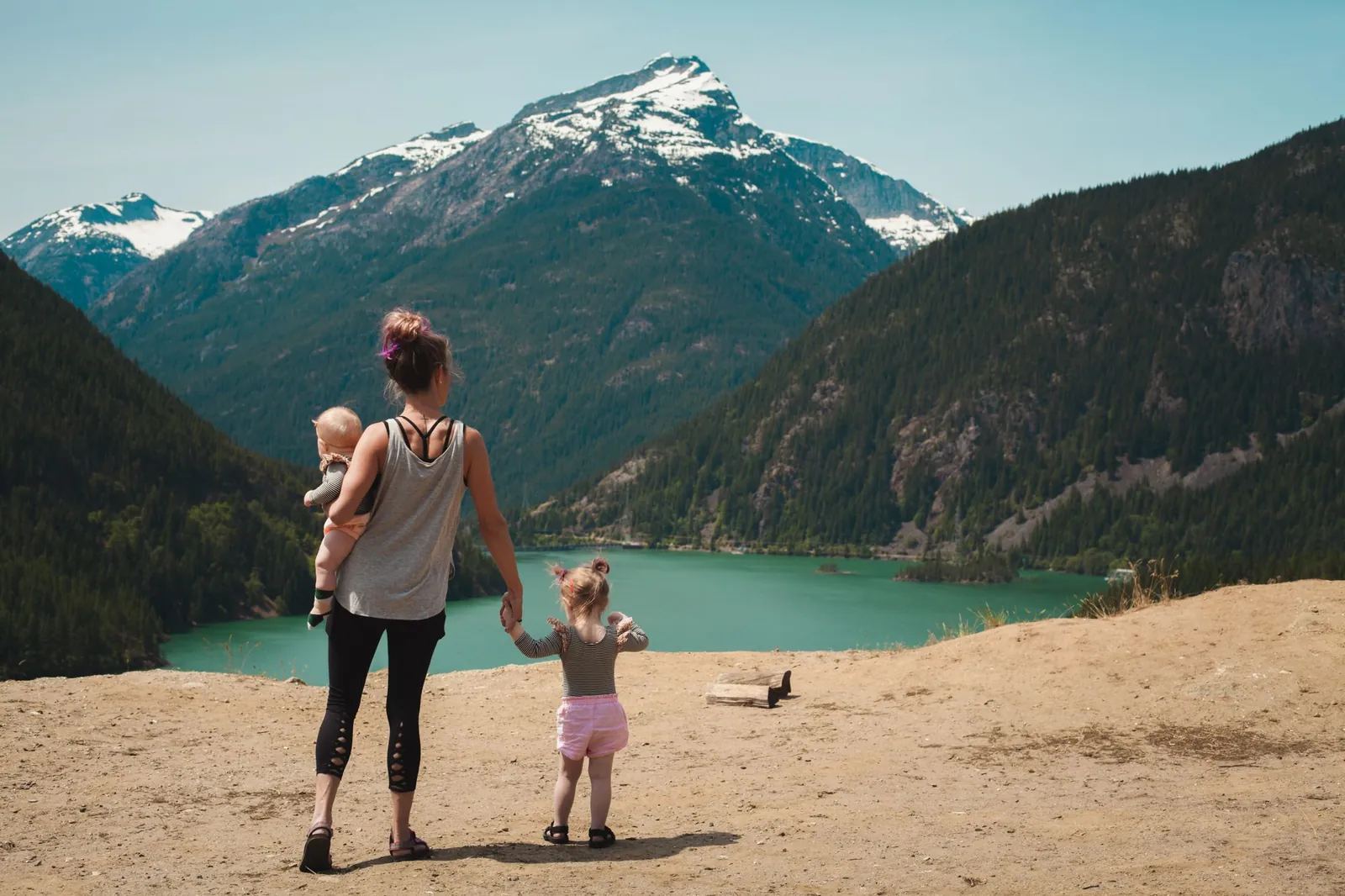 Mother and two young children looking out over a mountain lake on a summer hike