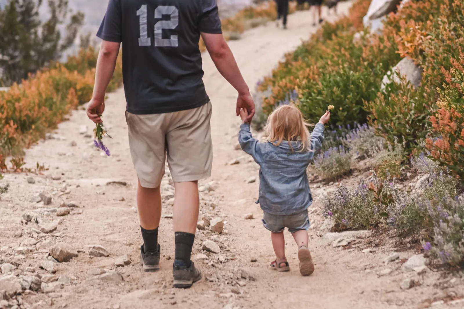 Father and young daughter walking a dirt trail together